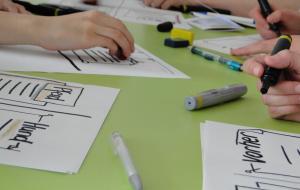 Hände mit Filzstiften gestalten Flipcharts auf einem Tisch